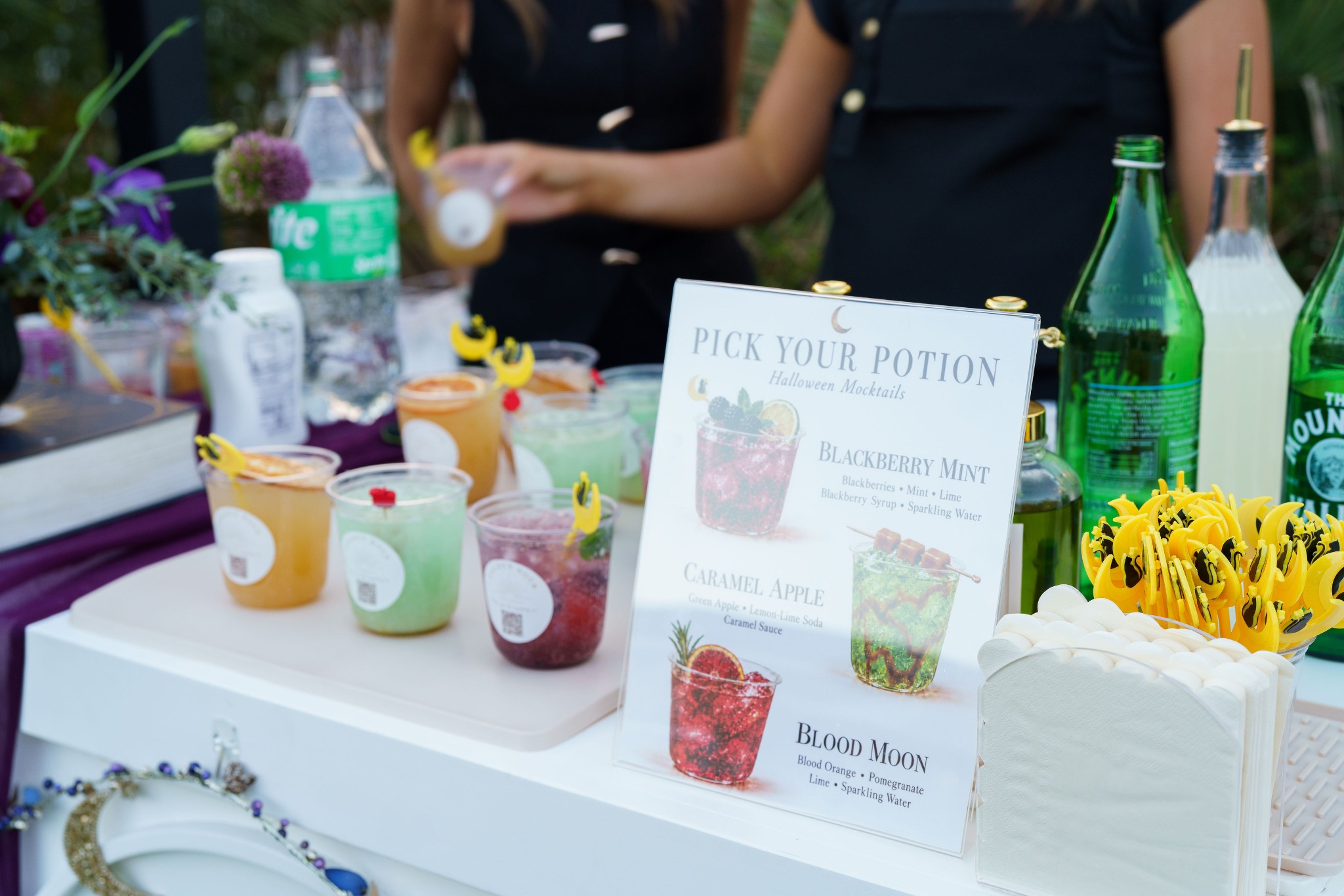 The Pick Your Potion Halloween mocktail menu beside Golden Hour Events drinks, yellow stirrers and white napkins