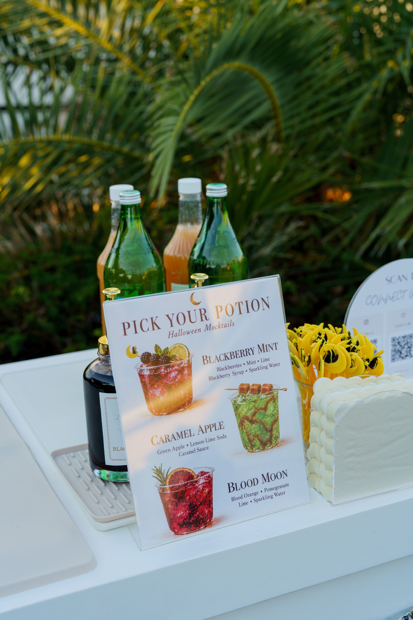 A close view of the Pick Your Potion menu listing Blackberry Mint, Caramel Apple and Blood Moon beside bottles and stirrers